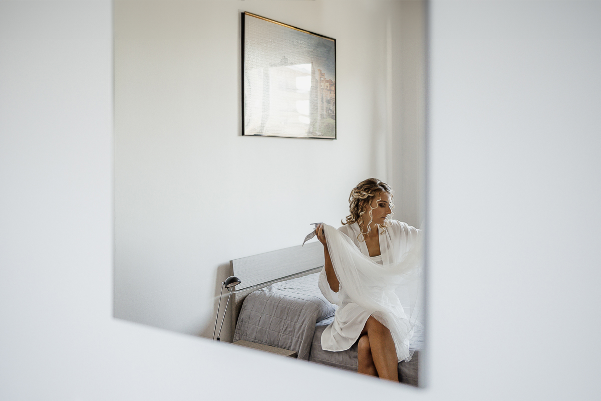 matrimonio a chieri, preparazione della sposa. Sposa seduta sul letto riflessa nello specchio