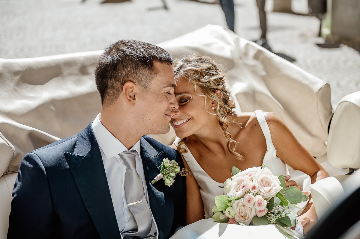 matrimonio a Chieri .Foto di coppia all'Arco Monumentale di Chieri. Sposi nell'auto scoperta maggiolino bianco d'epoca. Sposo che bacia la sposa sulla fronte