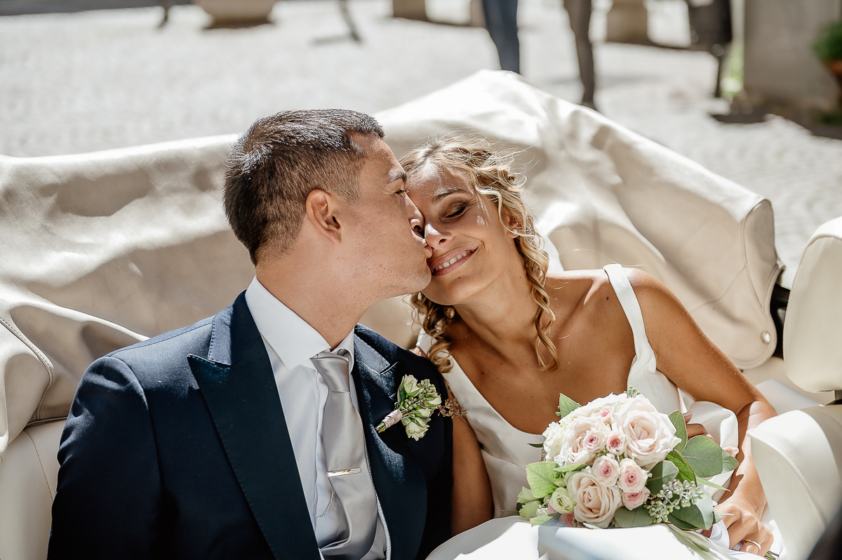 matrimonio a Chieri .Foto di coppia all'Arco Monumentale di Chieri. Sposi nell'auto scoperta maggiolino bianco d'epoca.Sposo che bacia la sposa