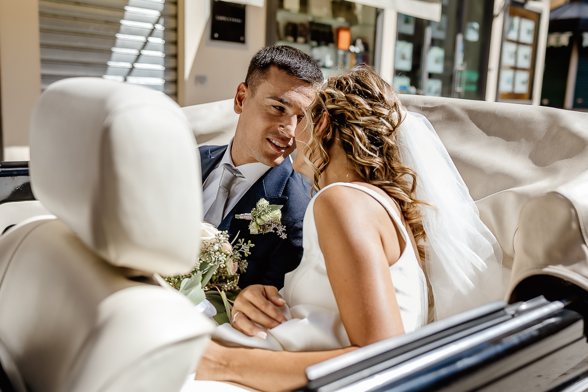 matrimonio a Chieri .Foto di coppia all'Arco Monumentale di Chieri. Sposi nell'auto scoperta maggiolino bianco d'epoca.sposi che si guardano.