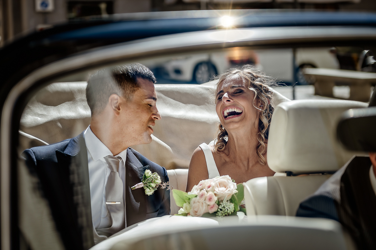 matrimonio a Chieri .Foto di coppia all'Arco Monumentale di Chieri. Sposi nell'auto scoperta maggiolino bianco d'epoca.sposa che ride