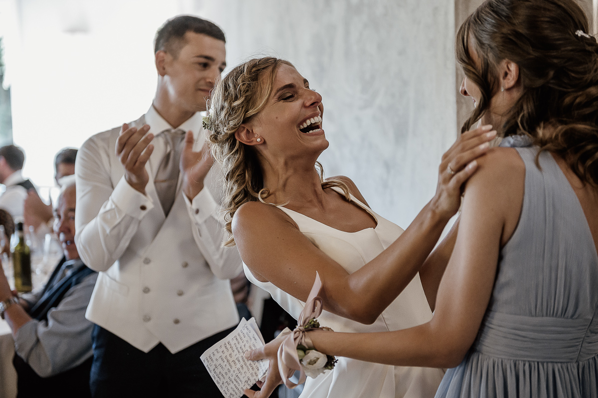 matrimonio al ristorante albergo Ca' Vittoria di Tigliole d'Asti.Sposa che ride abbracciando la sua testimone