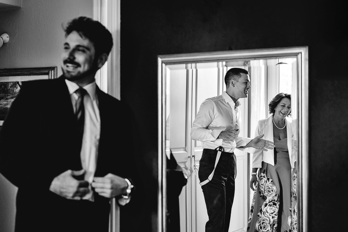 matrimonio a Chieri, preparazione dello sposo, testimone sfocato e sposo e mamma riflessi nello specchio