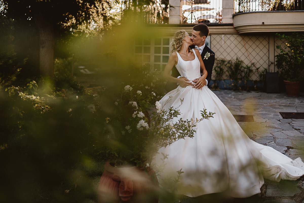 matrimonio al ristorante albergo Ca' Vittoria di Tigliole d'Asti.Foto di coppia.Sposi che si baciano dietro ad un cespuglio sfocato.