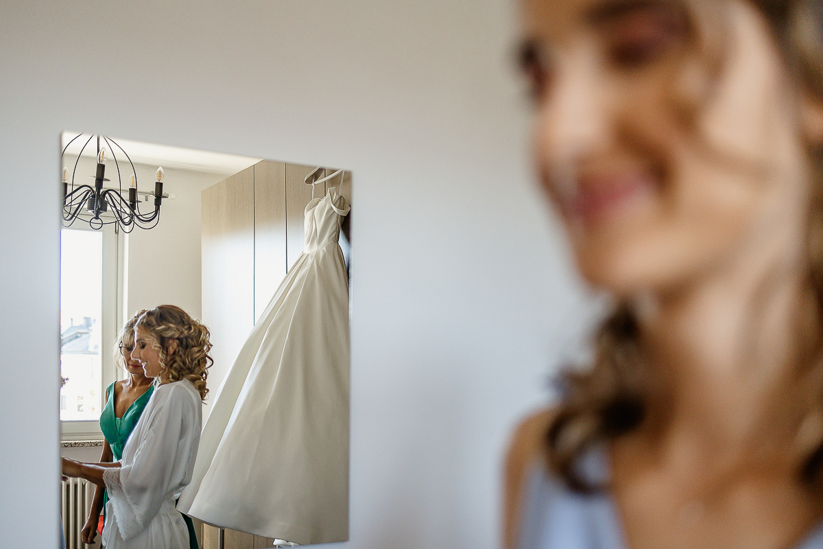 matrimonio a Chieri, preparazione della sposa, sposa riflessa nello specchio con l'abito appeso