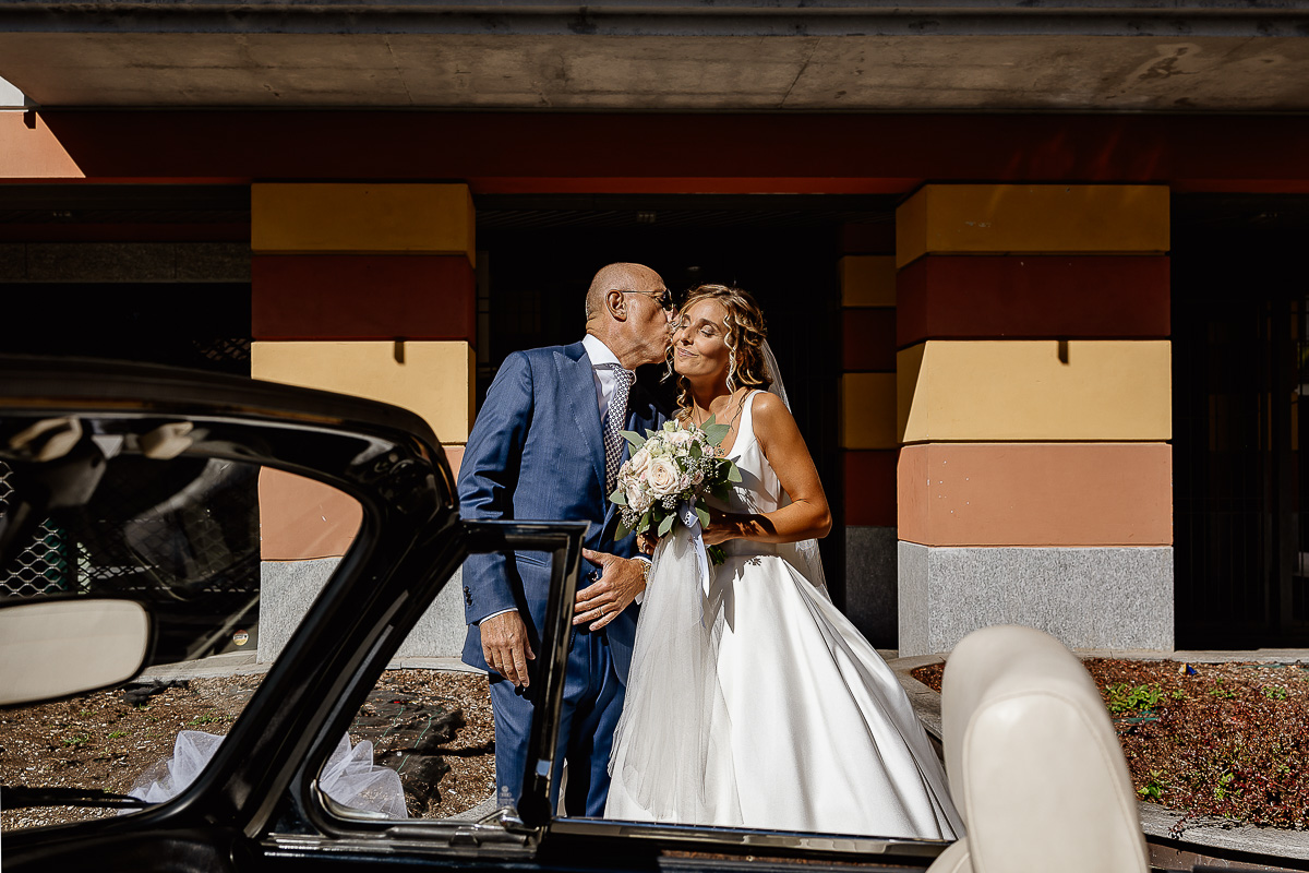 matrimonio a Chieri, preparazione della sposa, sposa che esce dalla casa e papà che la bacia su di una guancia.