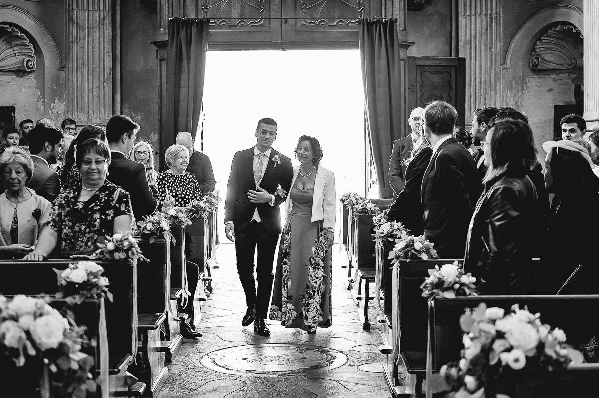 matrimonio a Chieri nella chiesa dei Ss. Bernardino e Rocco. sposo che percorre la navata al braccio della mamma. Bianco e nero.