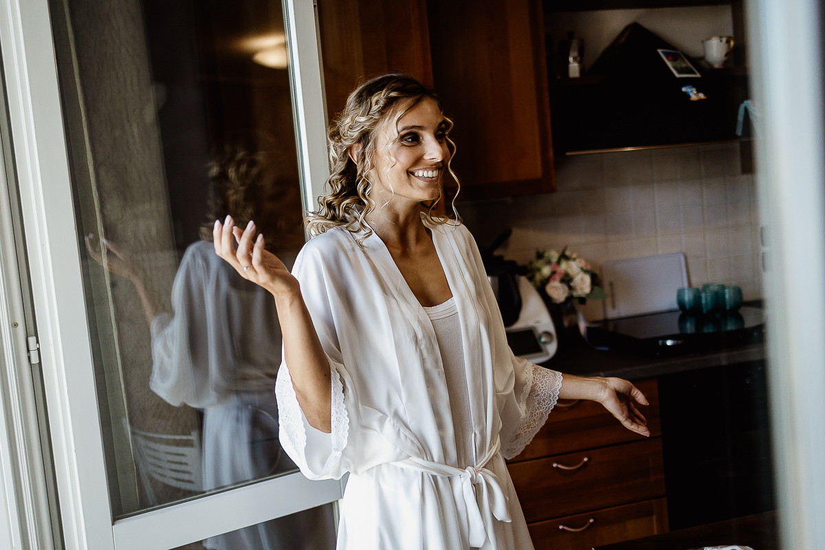 matrimonio a Chieri, sposa che ride davanti alla porta finestra con riflesso