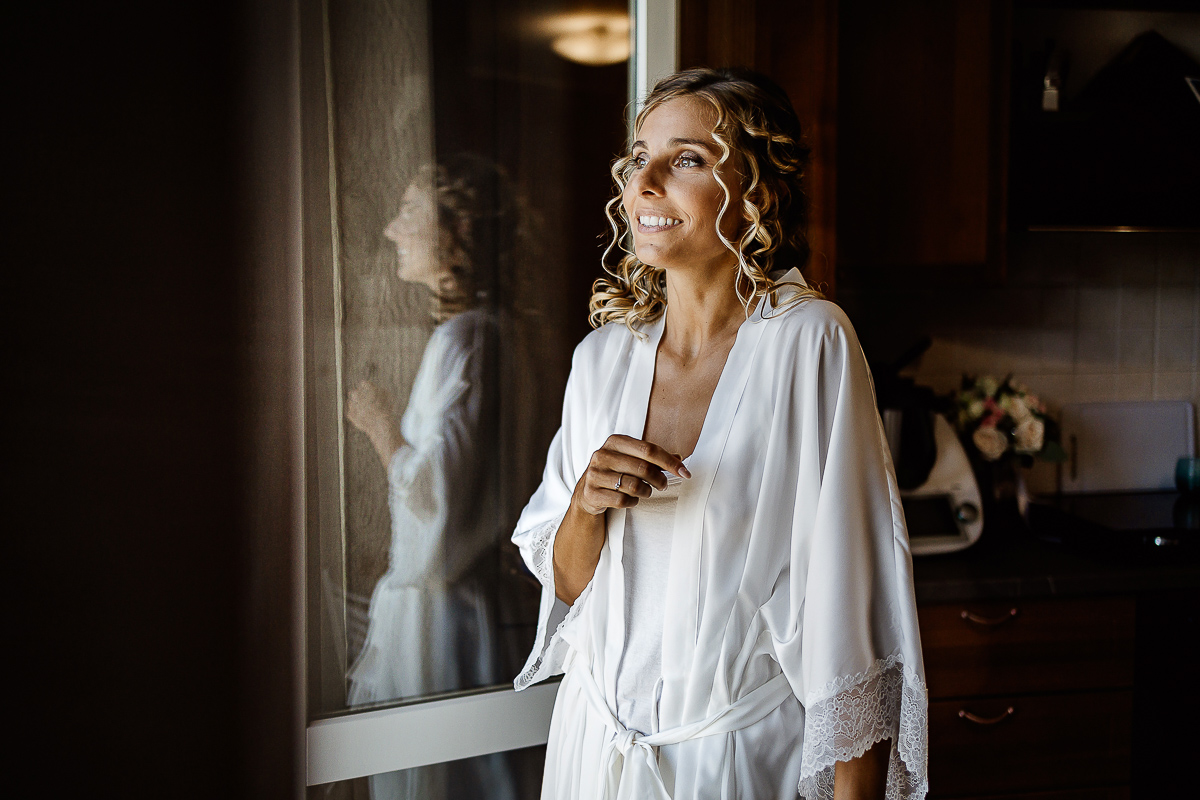 matrimonio a Chieri, sposa che ride davanti alla porta finestra con riflesso