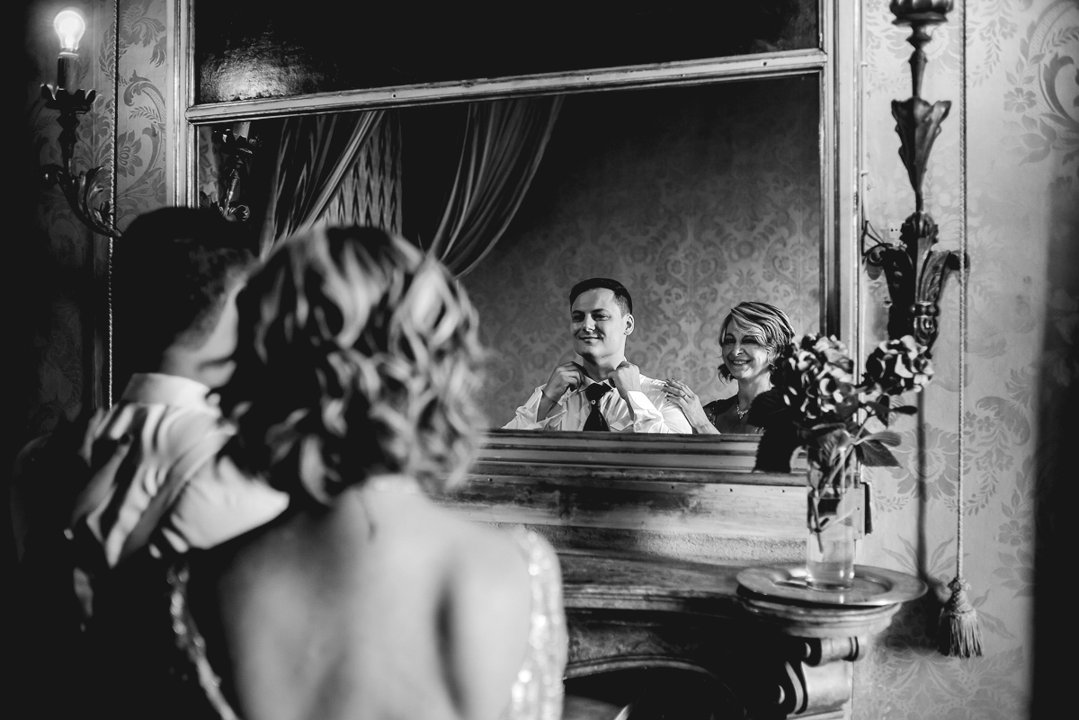 Matrimonio al Castello Canalis di Cumiana(TO). Sposo e mamma che si riflettono nella specchiera sul camino