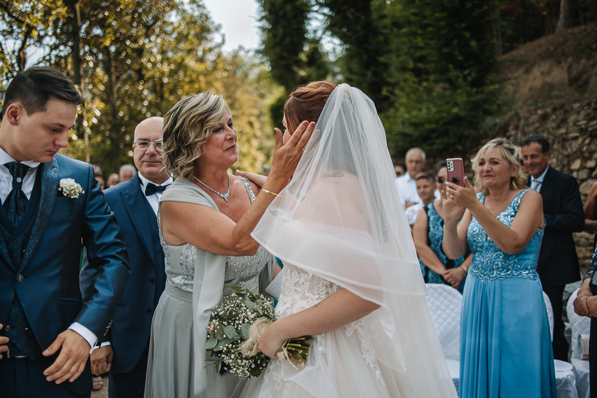 Matrimonio al Castello Canalis di Cumiana(TO). Cerimonia. Mamma dello sposo che accarezza la sposa.