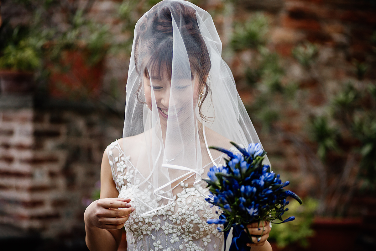 Castello di Collegno, matrimonio cinese. Cerimonia occidentale.Ritratto della sposa che ride sotto il velo.