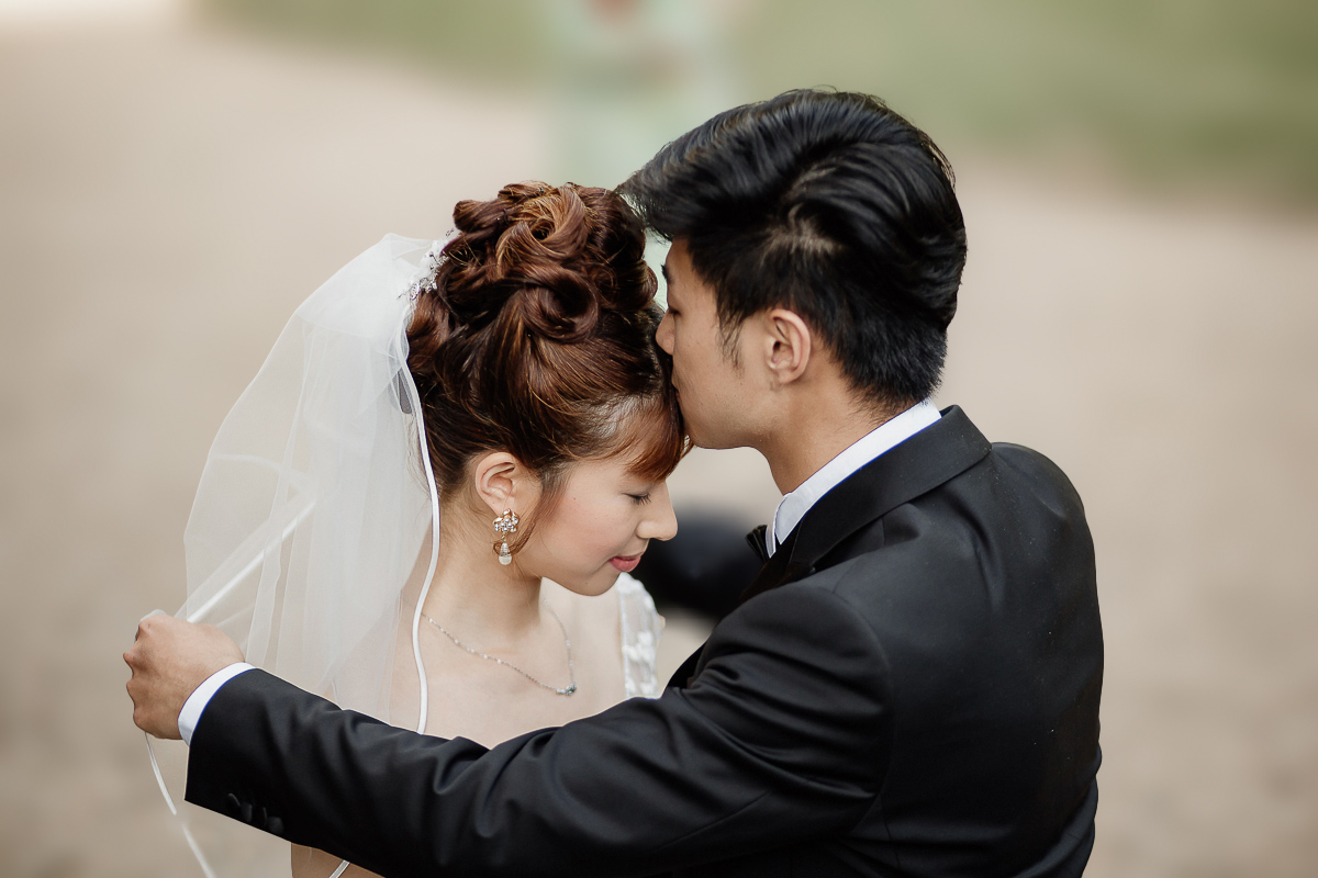 Castello di Collegno, matrimonio cinese. Cerimonia occidentale.Sposo bacia la sposa sulla fronte.