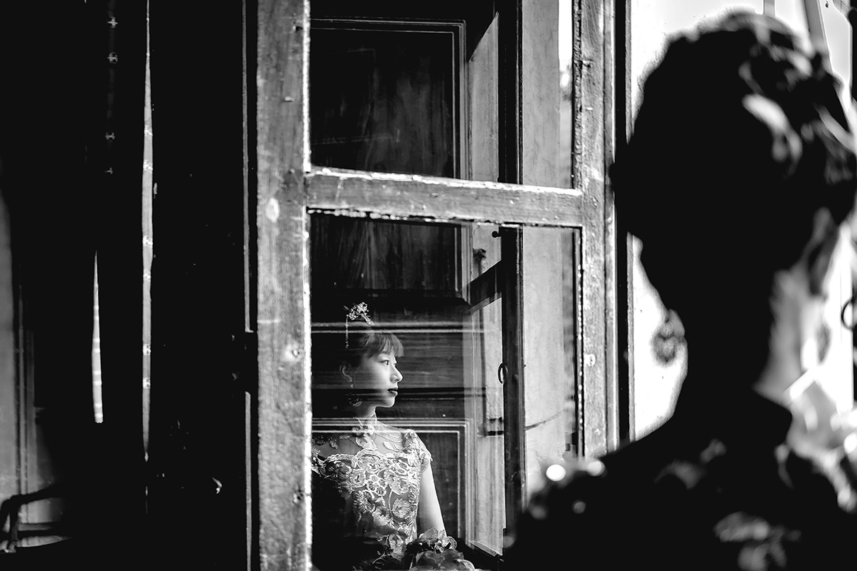 Castello di Collegno, matrimonio cinese. Cerimonia tradizionale. Preparazione della sposa. Ritratto della sposa con l'abito tradizionale rosso ed oro. Sposa riflessa in una finestra.