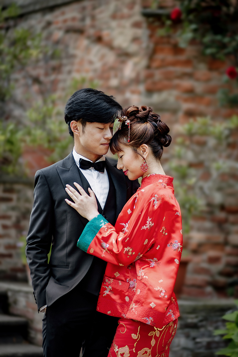 Castello di Collegno, matrimonio cinese. Cerimonia tradizionale. Sessione fotografica di coppia. sposa indossa una giacca tradizionale cinese di seta rossa ricamata. Ritratto intimo degli sposi.