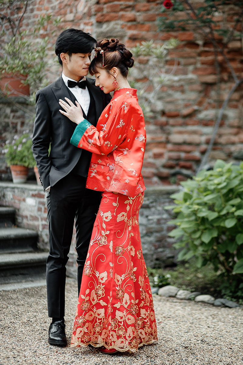 Castello di Collegno, matrimonio cinese. Cerimonia tradizionale. Sessione fotografica di coppia. sposa indossa una giacca tradizionale cinese di seta rossa ricamata. Ritratto intimo degli sposi.