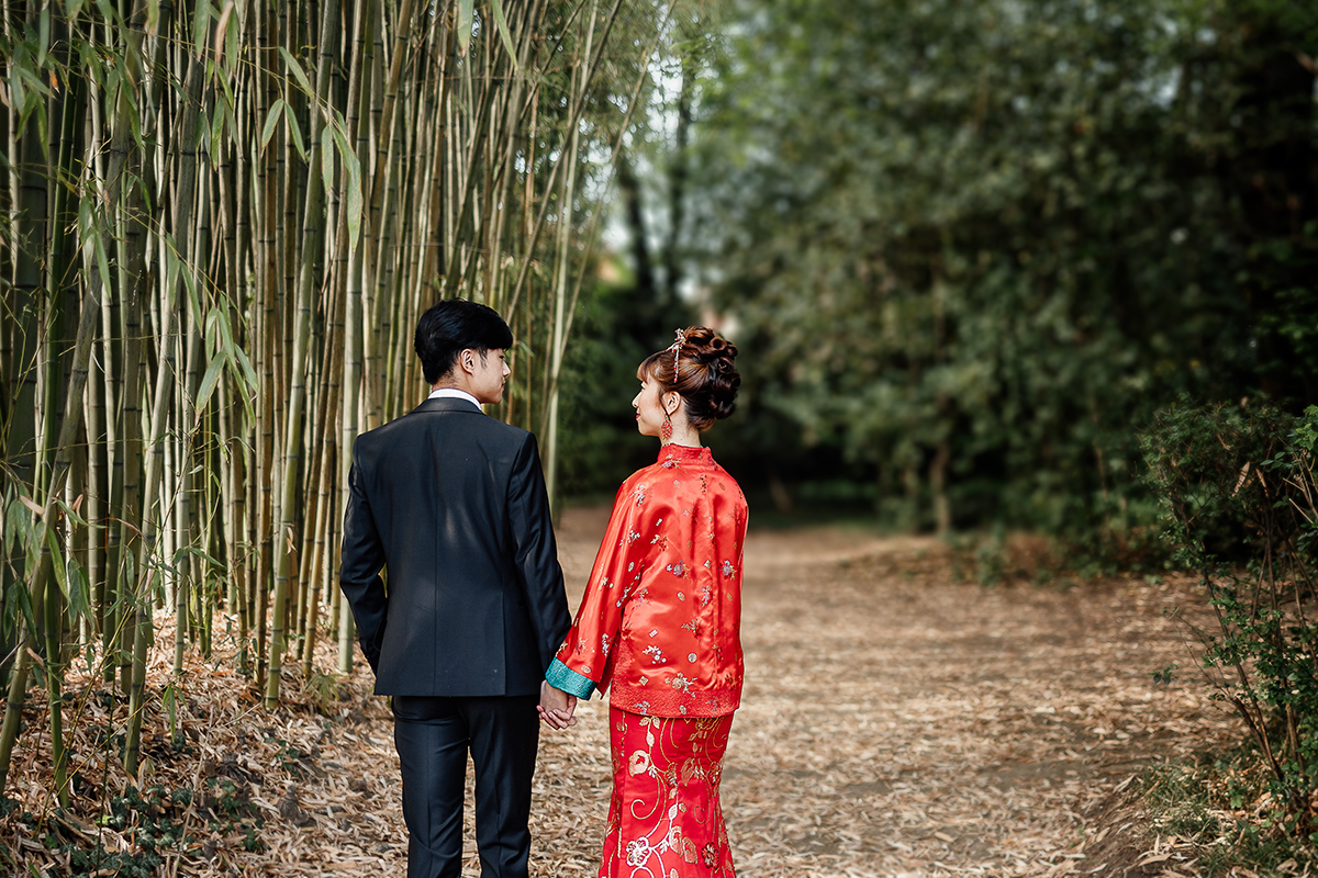 Castello di Collegno, matrimonio cinese. Cerimonia tradizionale. Sessione fotografica di coppia. sposa indossa una giacca tradizionale cinese di seta rossa ricamata. Sposi camminano nel bosco di bambù.