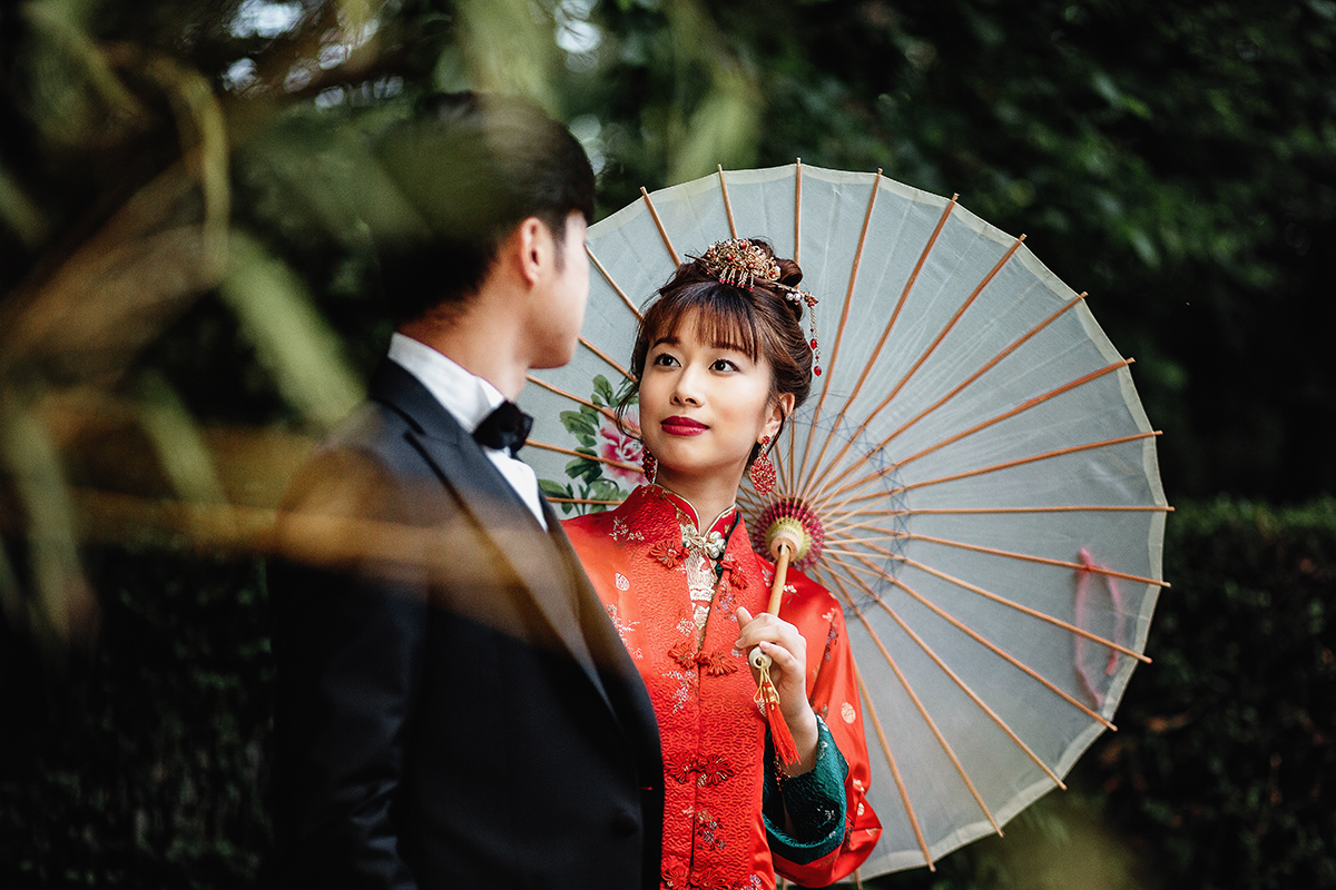 Castello di Collegno, matrimonio cinese. Cerimonia tradizionale. Sessione fotografica di coppia. sposa indossa una giacca tradizionale cinese di seta rossa ricamata.Sposi camminano nel bosco dei bambù Sposa con ombrellino di carta tradizionale cinese.