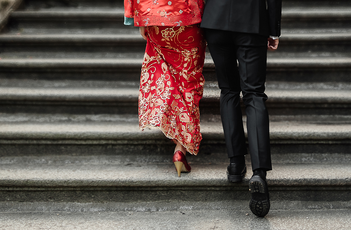 Castello di Collegno, matrimonio cinese. Cerimonia tradizionale. Sessione fotografica di coppia. sposa indossa una giacca tradizionale cinese di seta rossa ricamata.Sposi camminano