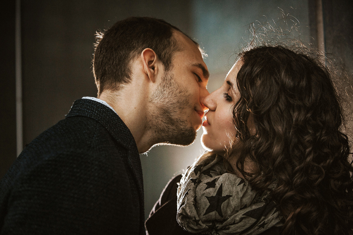 Engagement a Torino nella stazione di Porta Susa. Bacio. Flash esterno dietro la coppia.