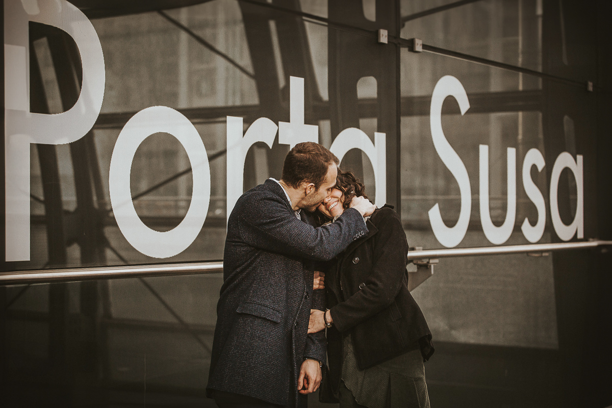 Engagement a Torino nella stazione di Porta Susa. la coppia si bacia davanti all'entrata della stazione.