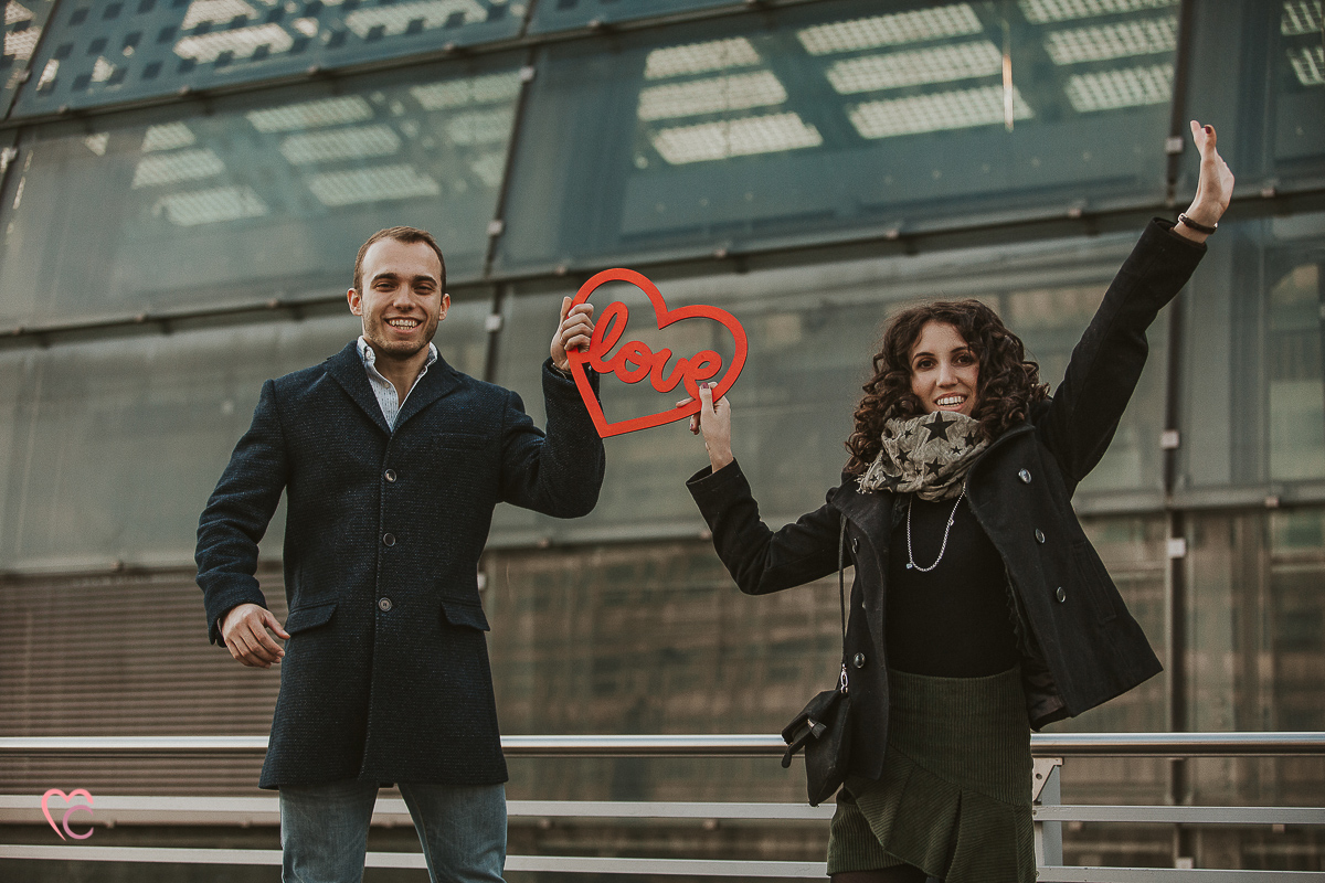 Engagement a Torino nella stazione di Porta Susa. La coppia si tiene in mano un cuore rosso con la scritta love