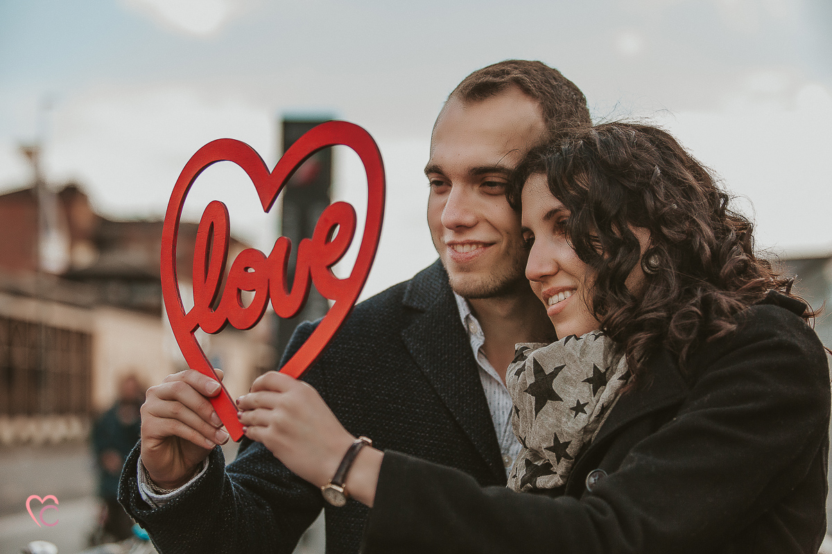 Engagement a Torino nella stazione di Porta Susa. La coppia si tiene in mano un cuore rosso con la scritta love