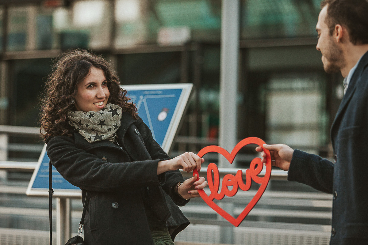 Engagement a Torino nella stazione di Porta Susa. La coppia si tiene in mano un cuore rosso con la scritta love