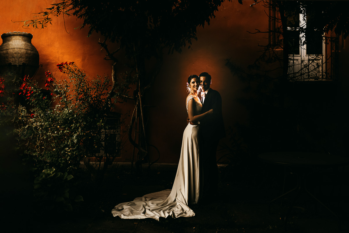 Castello Rosso di Costigliole di Saluzzo. Destination wedding. Sessione di coppia al tramonto. Bacio degli sposi davanti ad una parrete color terracotta. Flash off camera dietro gli sposi