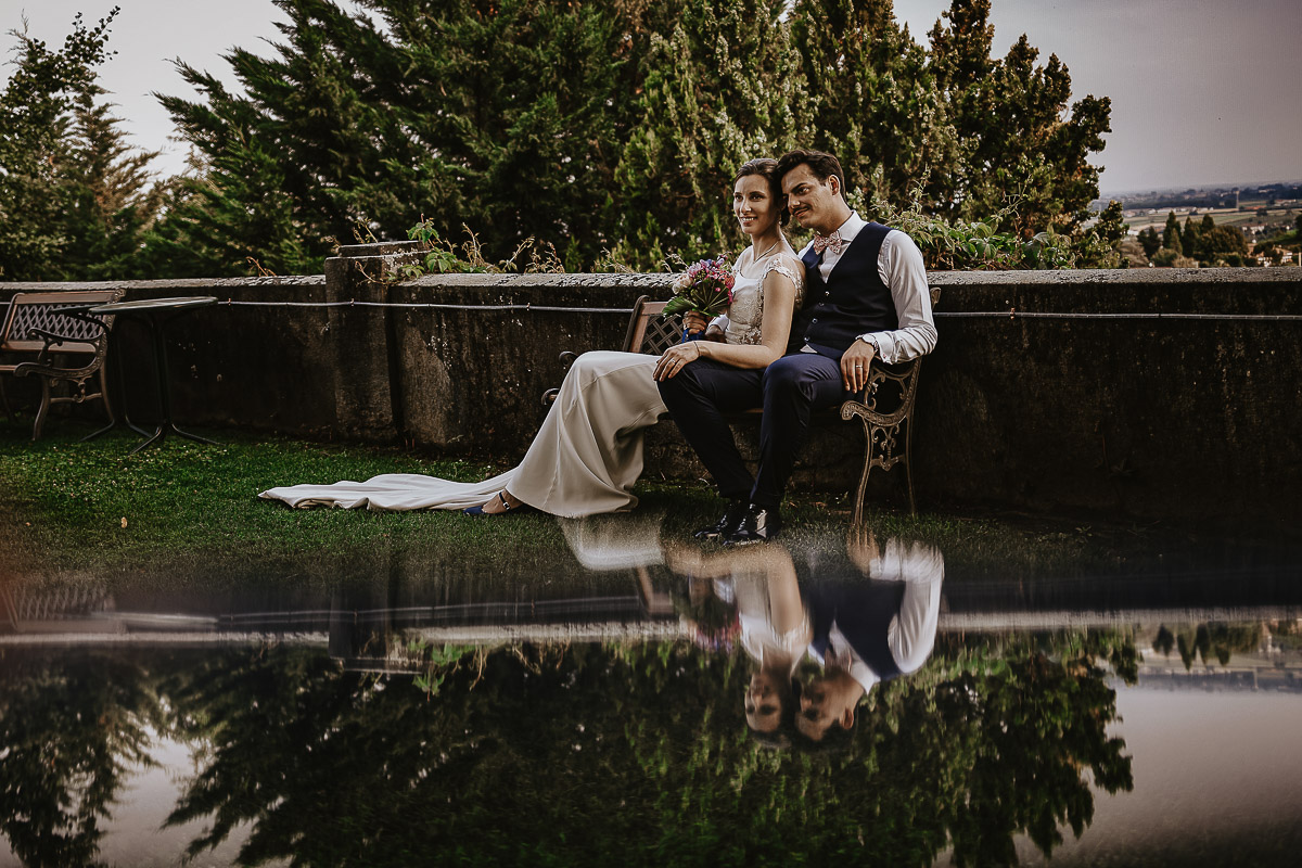Castello Rosso di Costigliole di Saluzzo. Destination wedding. Sessione di coppia al tramonto.Sposi seduti su di una panchina. Foto riflessa.