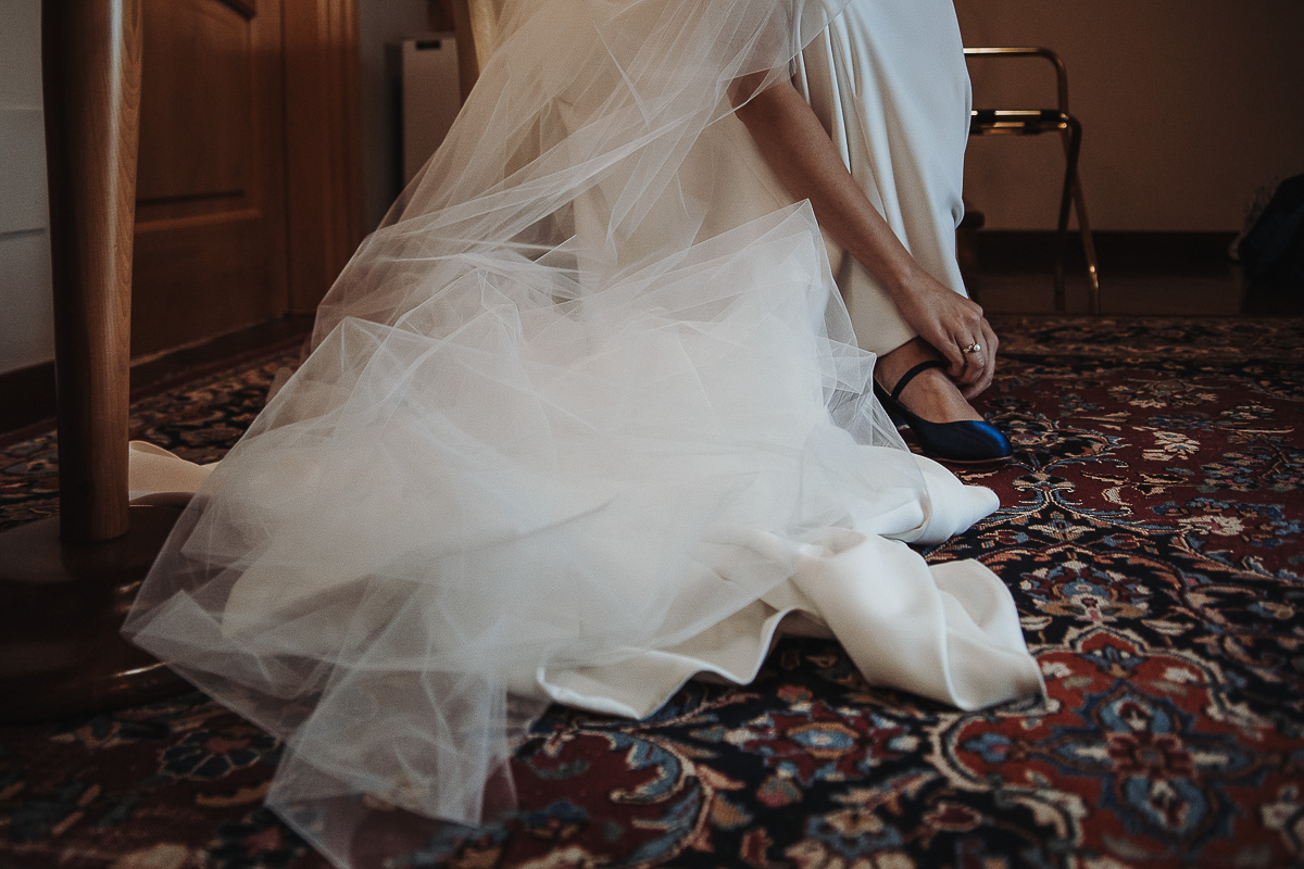 Castello Rosso di Costigliole di Saluzzo. Destination wedding. Sposa si abbottona le scarpe.
