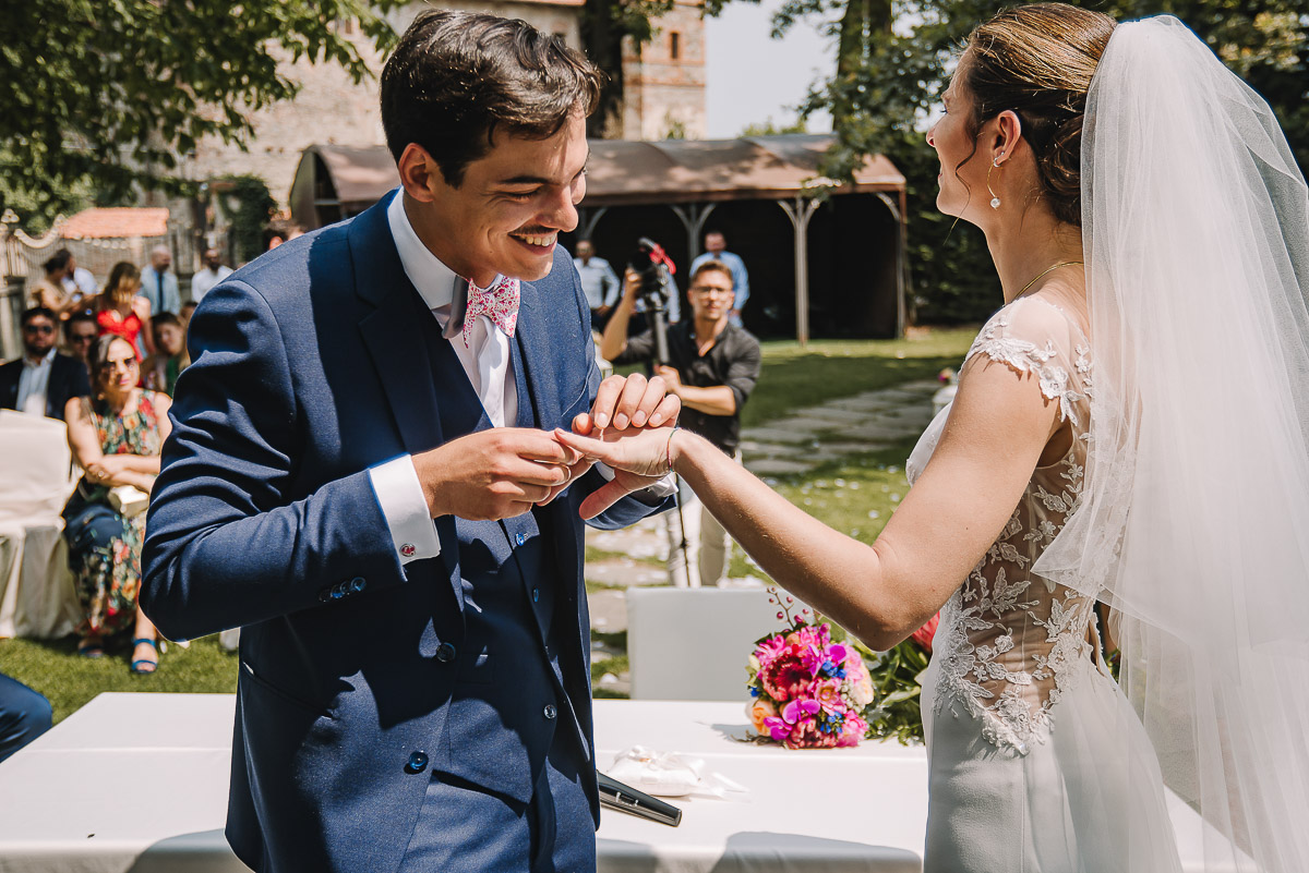 Castello Rosso di Costigliole di Saluzzo. Destination wedding. Cerimonia.Sposo infila l'anello al dito della sposa.