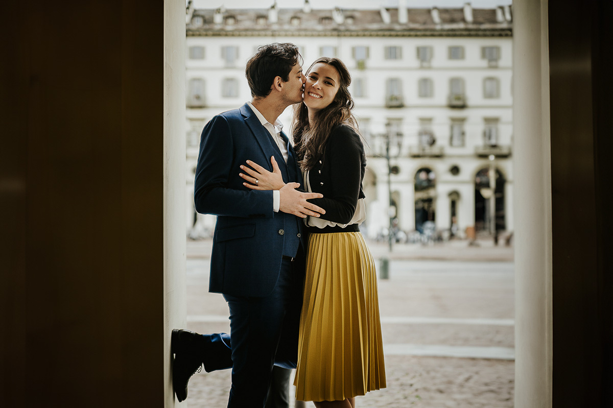 Engagement a Torino, in piazza Vittorio Veneto a Torino di Sara e Gabriel. Coppia sotto un arco dei portici Gabriel bacia Sara sulla guancia.