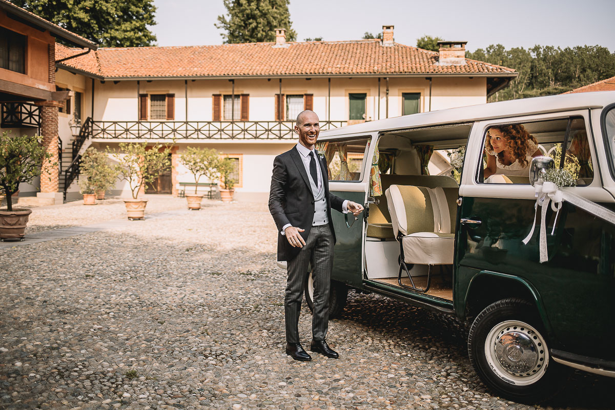 Matrimonio nella Villa dei Marchesi di Moncrivello. Servizio di coppia.Sposo che tiene la portiera del furgoncino Van della Wolkswagen aperta per far scendere la sposa