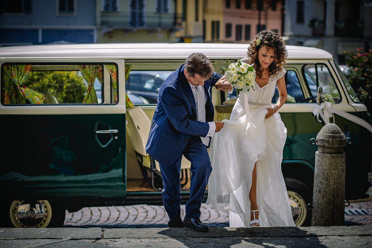 Matrimonio nella Chiesa Parrocchiale di Strambino. Arrivo della sposa con lo storico furgoncino Wolkswagen Van. Padre che aiuta la sposa con l'abito.