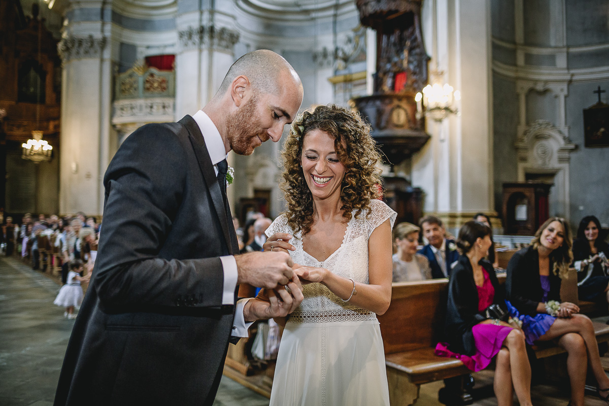 Matrimonio nella Chiesa Parrocchiale di Strambino. Sposo che infila l'anello alla sposa e sposa che ride.