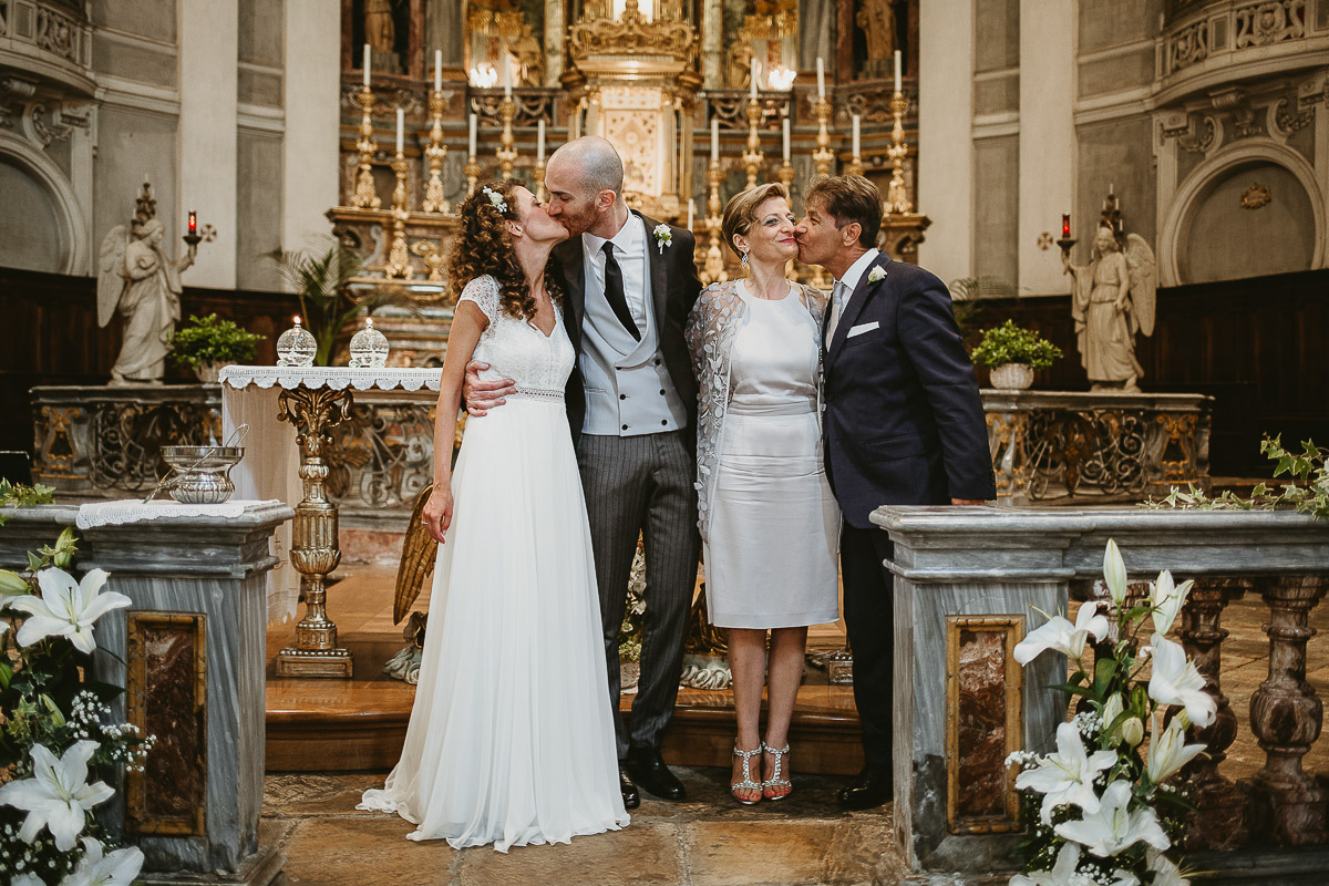 Matrimonio nella Chiesa Parrocchiale di Strambino. Foto con i genitori della sposa. Tutti si baciano.