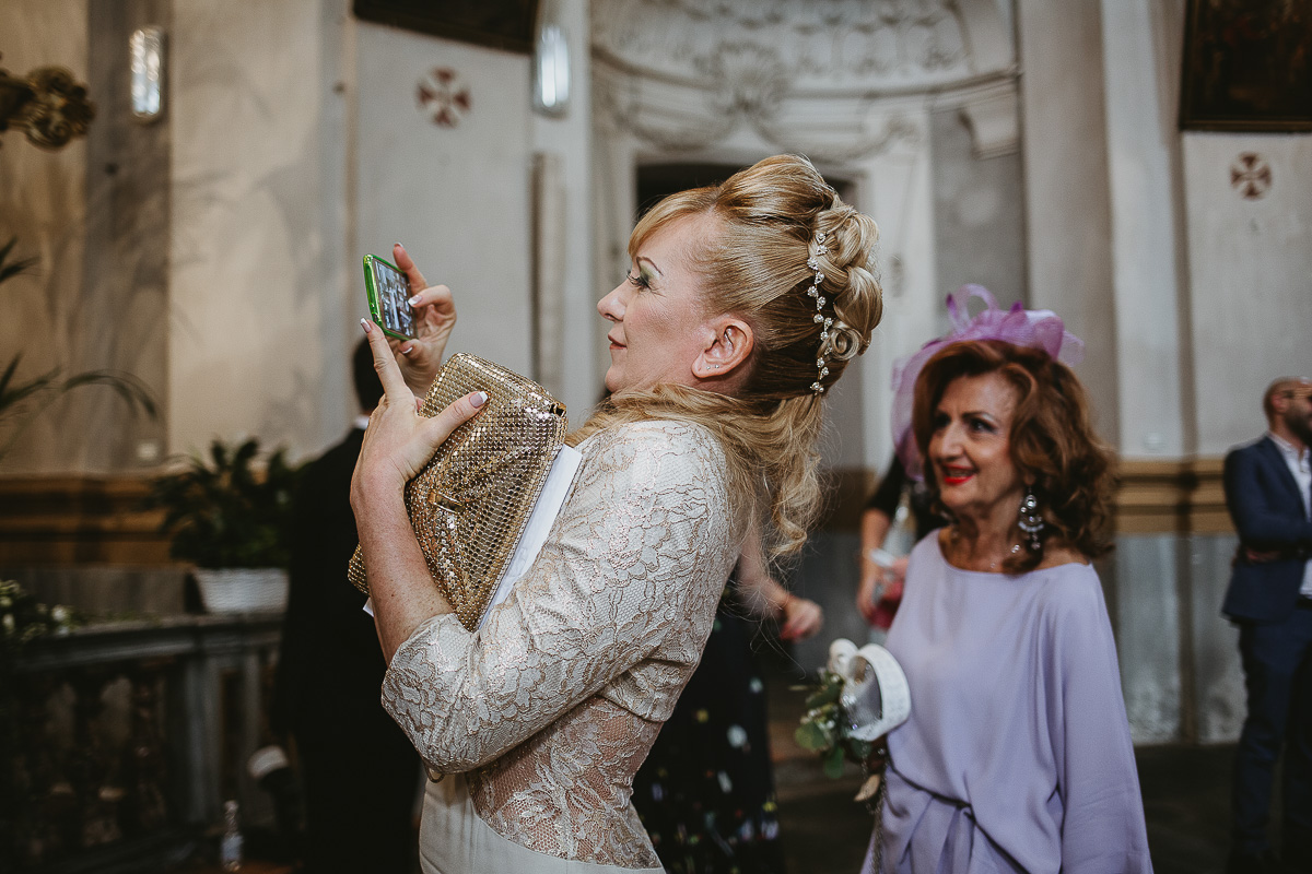 Matrimonio nella Chiesa Parrocchiale di Strambino. Invitata che fa foto con il cellulare.