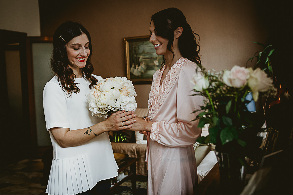 Matrimonio in centro a Torino. Preparazione della sposa. Wedding planner consegna il bouquet alla sposa.