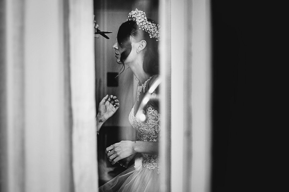 Matrimonio a Torino. Preparazione della sposa.Sposa vista attraverso il vetro della porta finestra
