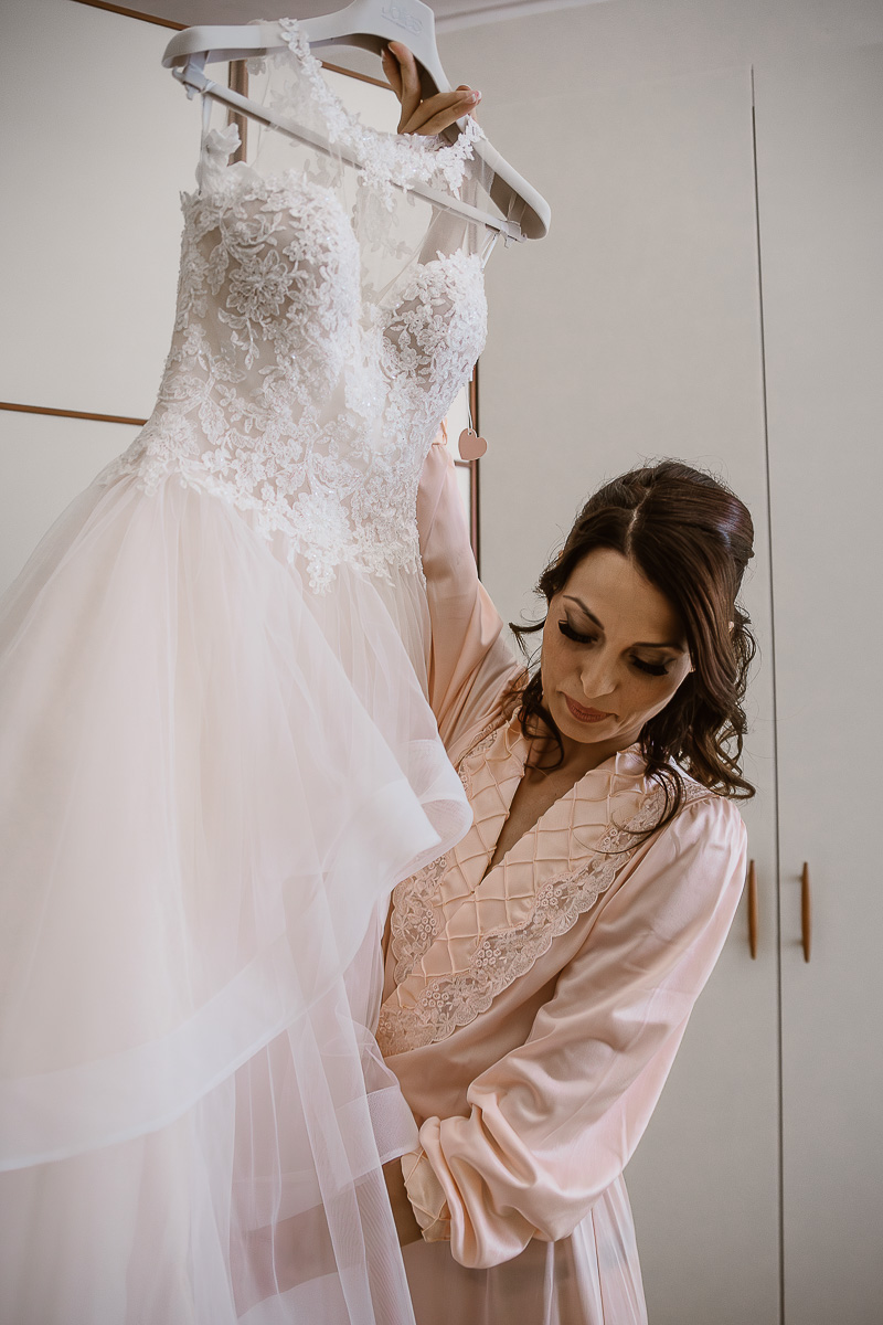 Matrimonio a Torino, preparazione della sposa. Sposa prende l'abito per indossarlo.