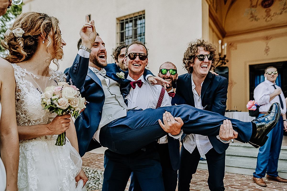 Matrimonio al castello di Cortanze. Aperitivo.Amici che prendono in braccio lo sposo