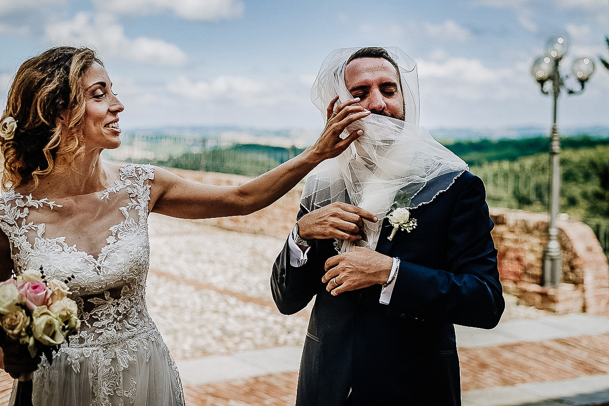 Matrimonio al castello di Cortanze. Aperitivo.Sposa che mette il velo allo sposo.