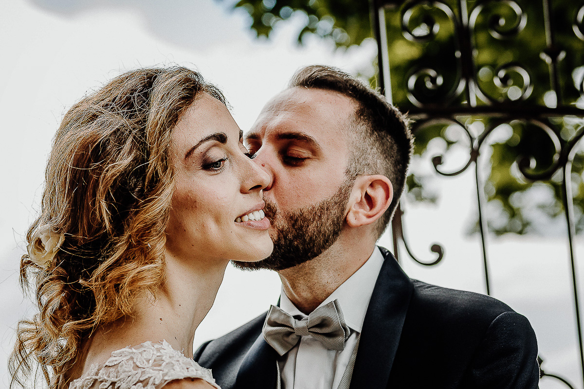Matrimonio al castello di Cortanze. Sessione di coppia. Sposo che bacia la sposa su di una guancia.