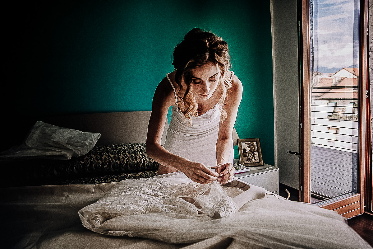 Matrimonio a Torino, preparazione della sposa.Sposa che sistema il vestito sul letto.