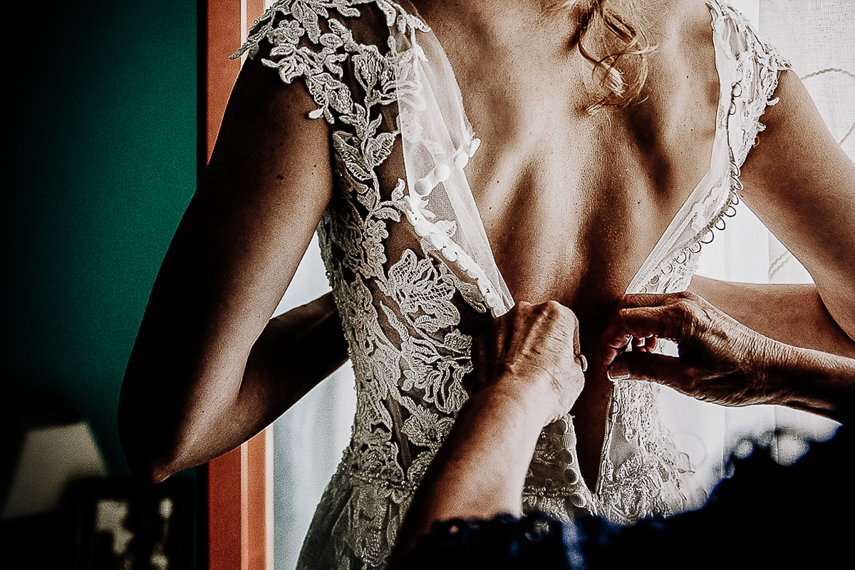 Matrimonio a Torino, preparazione della sposa.Madre che abbottona l'abito della sposa.
