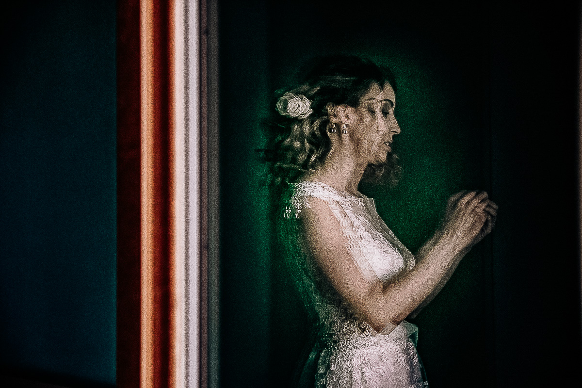 Matrimonio a Torino, preparazione della sposa.Ritratto della sposa attraverso il vetro della porta finestra.