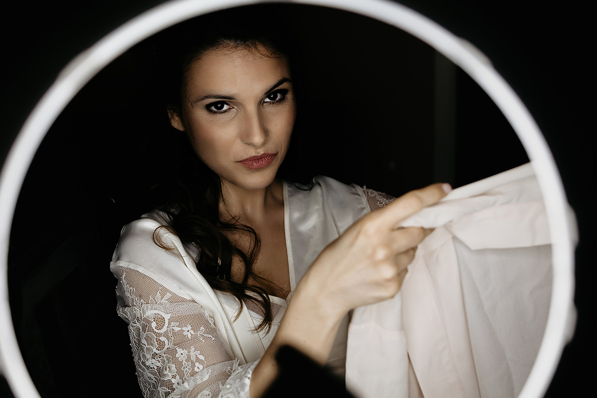 Matrimonio a Torino. Preparazione della sposa. Sposa illuminata da una ring light che mostra il regalo delle amiche