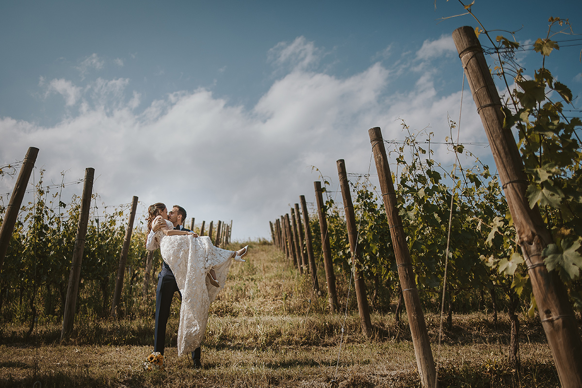 Tenuta Fontanfredda, Guidoristorante. Villa reale.Sessione fotografica degli sposi tra le vigne. Sposo prende in braccio la sposa.