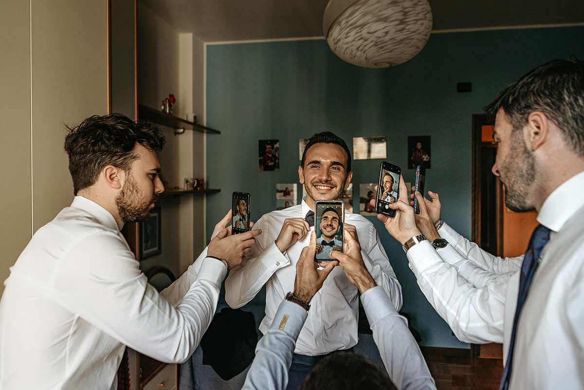 Matrimonio a Torino. Preparazione dello sposo. Amici che fanno le foto con il cellulare allo sposo.